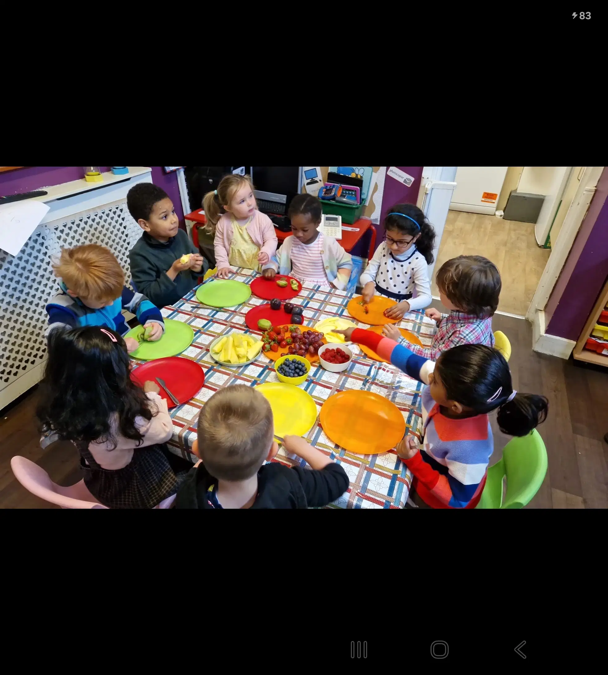 Children sharing fruit at a nursery table